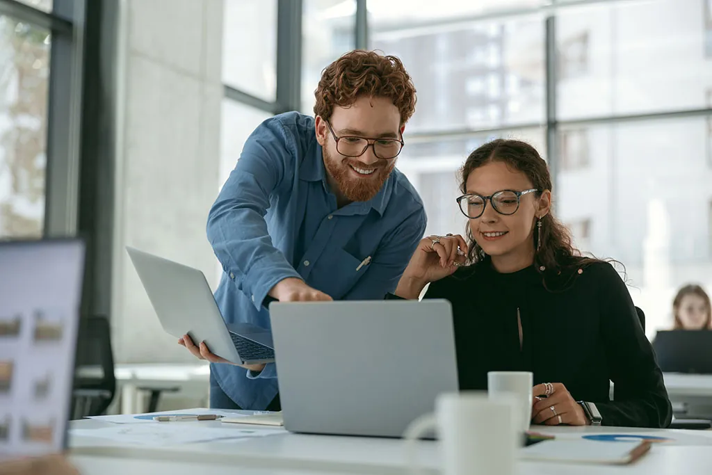 Two people discussing KPIs at a laptop