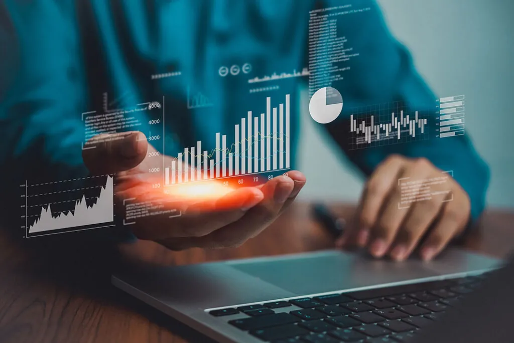 Hand with glowing charts above a laptop