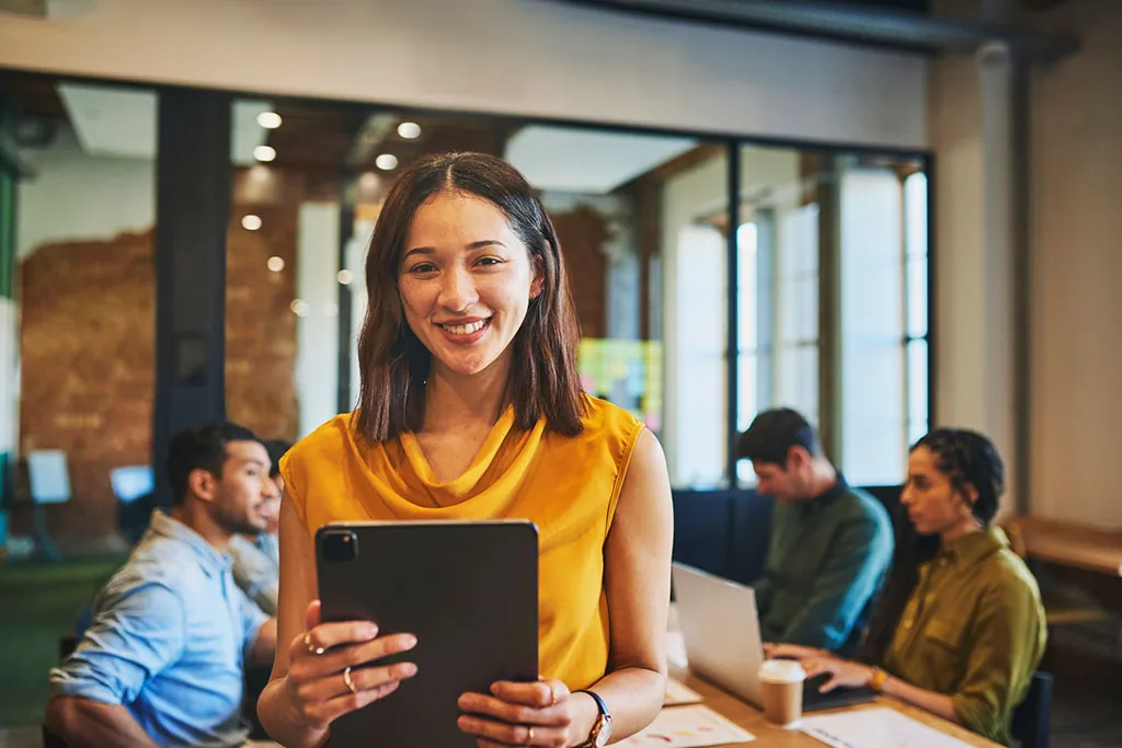Smiling woman with a tablet in a team meeting